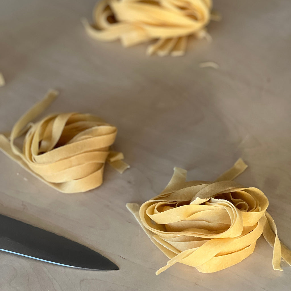 Pasta nests on a cutting board with a knife